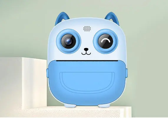 Appareil photo instantané enfant PrintPix™ bleu vu de face, avec oreilles de chat et fente d’impression.