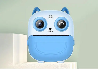 Appareil photo instantané enfant PrintPix™ bleu vu de face, avec oreilles de chat et fente d’impression.
